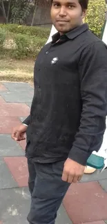 Man in black shirt standing in a park playground setting.