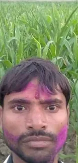 Man with colorful face in a green cornfield.