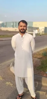 Man in white kurta standing outdoors on a sunny day.