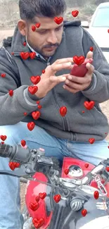 Man looking at smartphone while sitting on a red motorcycle.