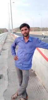 Man standing on highway bridge with serene sky backdrop.