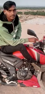 Man sitting on a red motorcycle with a landscape view.