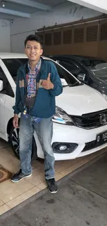 Man posing with a white car in a showroom, showcasing modern style.