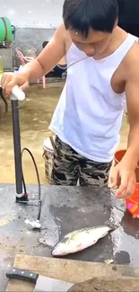 Man cleaning a fish outdoors on a table.