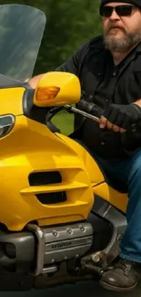 A man riding a yellow motorcycle on the road.