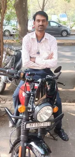 Man on a parked red motorcycle on an urban street.