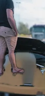 Man standing on a car with open hood on the road.