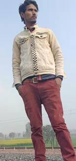 Man in casual attire on railway track with blue sky.