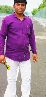 Man in purple shirt standing on road.