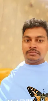 Man in light blue shirt with butterfly on artistic background.