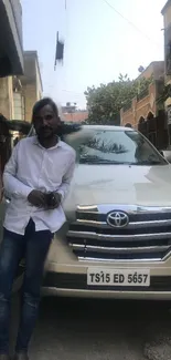 Man leaning on a white SUV parked in an urban street setting.