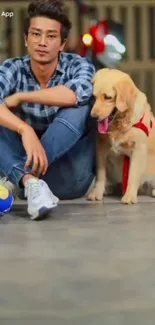 Man in plaid shirt sitting with Labrador and ball.