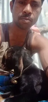 Man cuddling a goat in warm daylight.