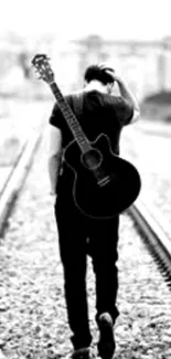 Monochrome photo of a guitarist walking on railway tracks from behind.