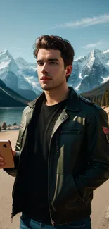 Man holding a phone in front of picturesque mountains and lake view.