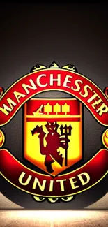 Manchester United red and yellow logo on mobile wallpaper.