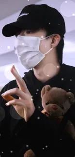 Person holds teddy bear, wearing mask and black attire.