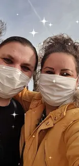 A smiling couple in masks with sparkling background outdoors.