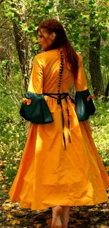 Woman in an orange medieval dress walks through lush green forest.