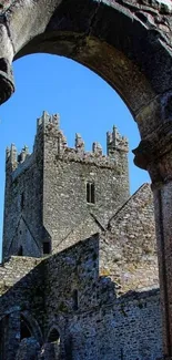 Stone castle framed by ancient arches under a blue sky.