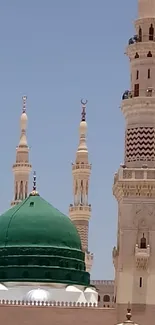 Green dome and minarets of Medina mosque under clear sky.