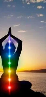 Silhouette yoga pose at sunset with colorful chakras glowing.