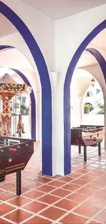 Mediterranean arcade with arches and foosball tables, featuring vibrant tiles.