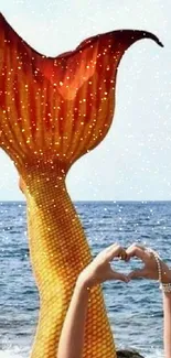 Mermaid tail rises from the ocean with a heart gesture in the foreground.