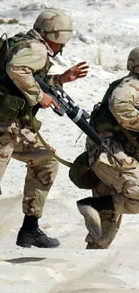 Two soldiers in camouflage running across a sandy desert.