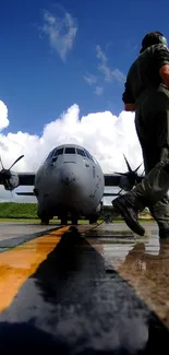 Military plane on wet runway under blue sky.