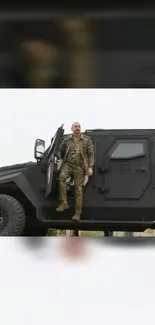 A soldier stands on a modern black military vehicle in a rugged setting.