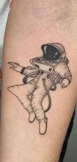 Minimalist tattoo of an astronaut design on an arm.