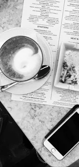 Black and white coffee and phone scene on a marble table.