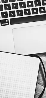 Minimalist black and white desk setup with laptop, notebook, and coffee cup.