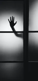 Black and white wallpaper with a hand silhouette on foggy glass.