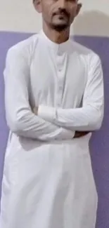 Person in a white kurta stands against a two-tone wall.