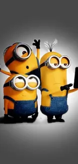 Three Minions taking a selfie on a gray background.