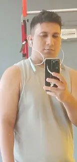 Man taking a gym mirror selfie with smartphone.