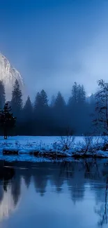 Misty blue mountains and forest reflected in calm water.