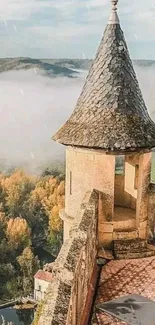 Castle tower overlooking a misty river valley covered in autumn foliage.