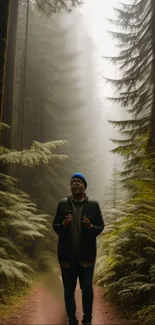 Person walking down a misty forest trail surrounded by tall trees.