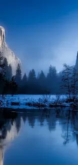 Misty mountain landscape with blue hue and river reflection.