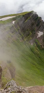 Misty mountain landscape with green slopes and cloudy sky.