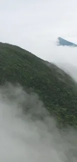 Misty mountain view with green hills and clouds.