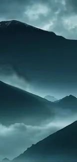 Misty mountain landscape with blue hues and clouds.