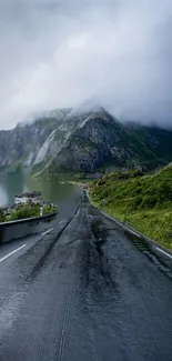 Misty mountain road with greenery and cloudy sky.