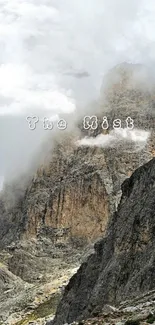 Misty mountain landscape with clouds enveloping rocky peaks.