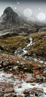 Misty mountain view with rocky stream and lush greens.