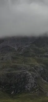 Misty mountain with green valleys and cloudy sky on phone wallpaper.