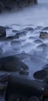 Misty shoreline with smooth rocks and fog.